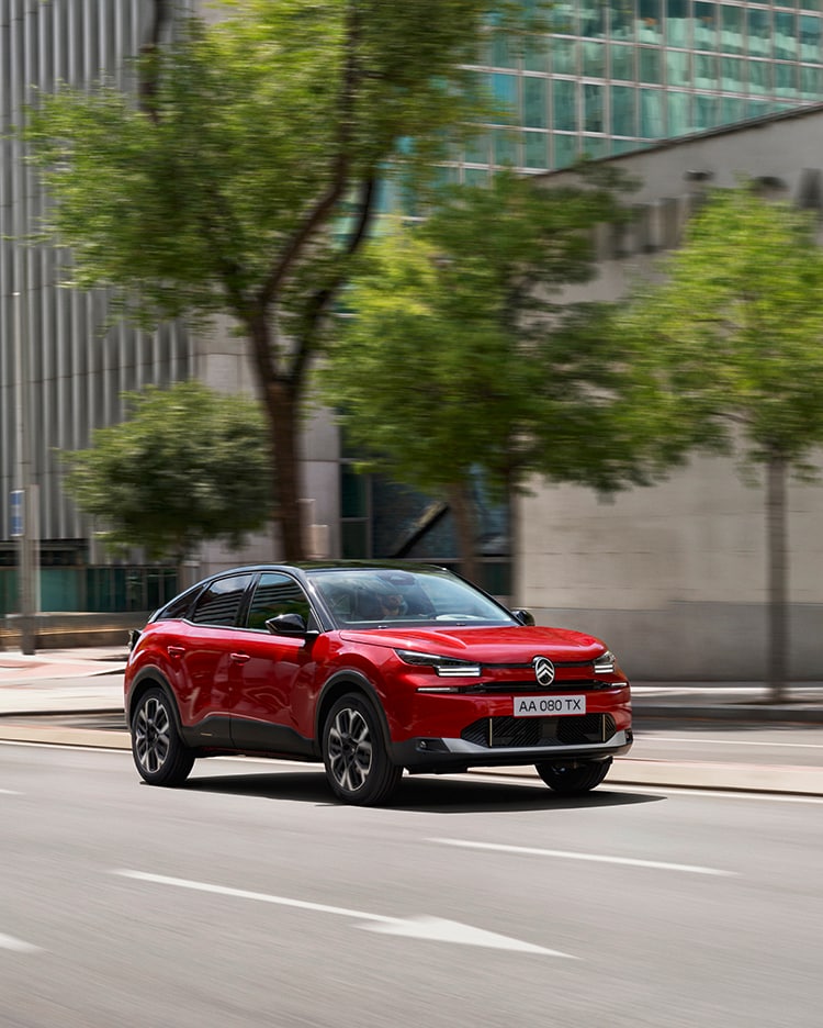 Citroën C3 Rouge avec coucher de soleil et ville en fond